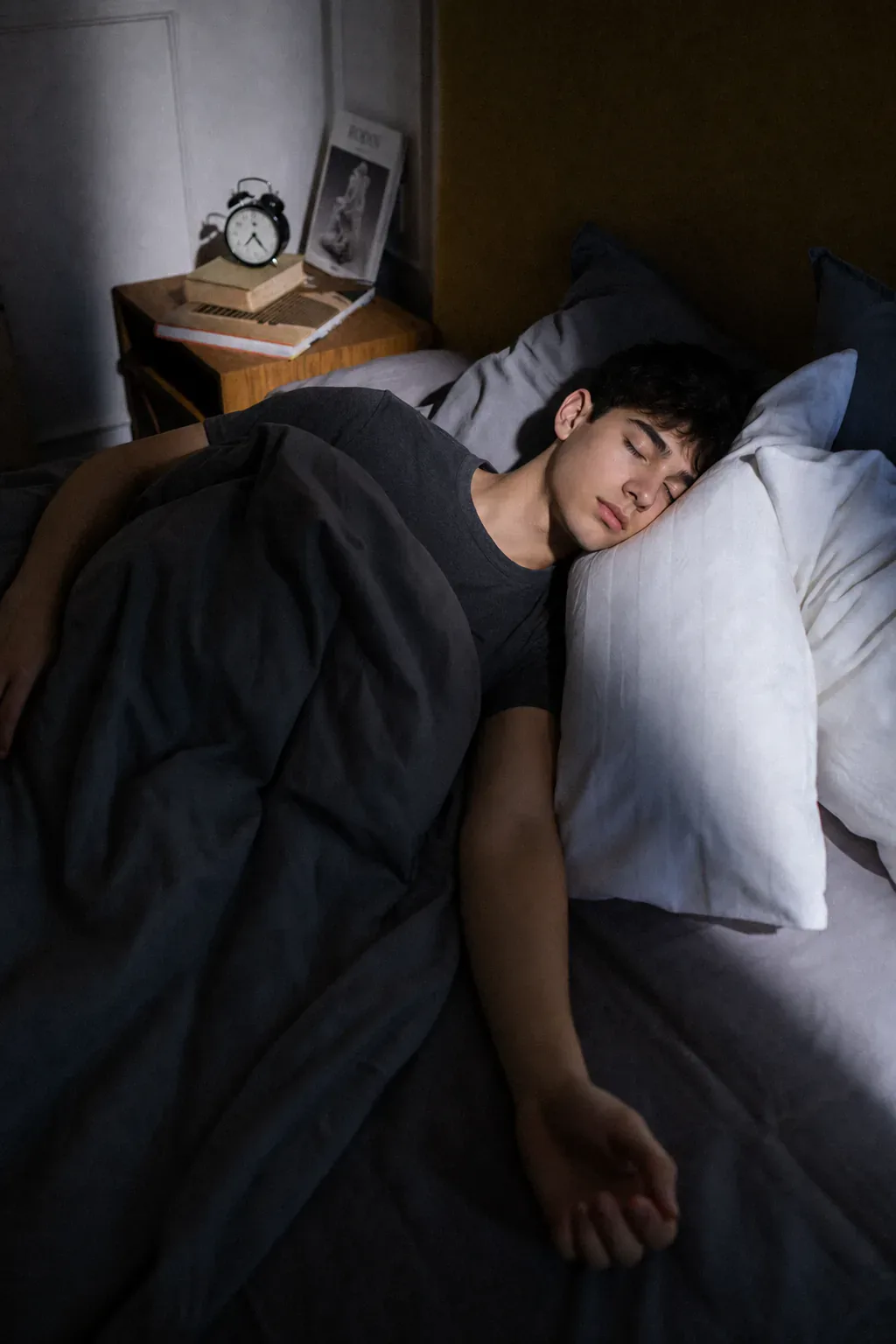 Ein Jugendlicher schläft im Morgenlicht in einem Bett.